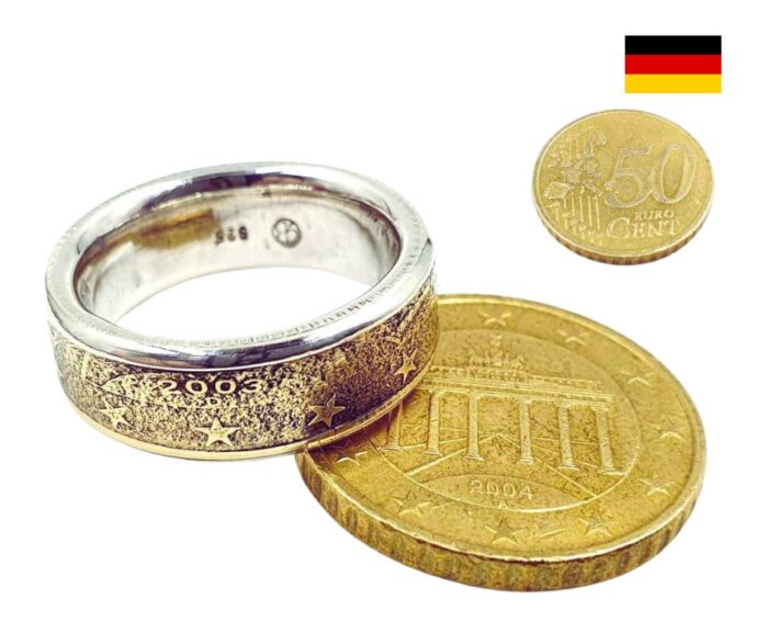 Einzigartiger Münzring Ein Meisterwerk der Handwerkskunst: Dieser atemberaubende Münzring wird aus einer originalen 50 Euro Cent Münze gefertigt und in hochwertigem 925er Silber eingefasst. Elegant und einzigartig verbindet er Tradition und modernes Design – perfekt für jeden Anlass. Gravurmöglichkeiten: Personalisieren Sie Ihren Ring mit einem individuellen Gravurtext und wählen Sie Ihr Wunschprägejahr. Material: Ringschiene: 925er Silber (nickelfrei) Münzring: originale 50 Cent Münze aus Messing Maße: Ringbreite: ca. 7,0 mm Ringstärke: ca. 1,5 mm Stil: Vintage – zeitlos und voller Charakter. Bitte beachten Sie: Die Bilder sind Beispielbilder. Der tatsächliche Ring kann in Form, Jahrgang und Farbe abweichen. Machen Sie diesen Ring zu einem persönlichen Erlebnis oder verschenken Sie ihn an jemand Besonderen!